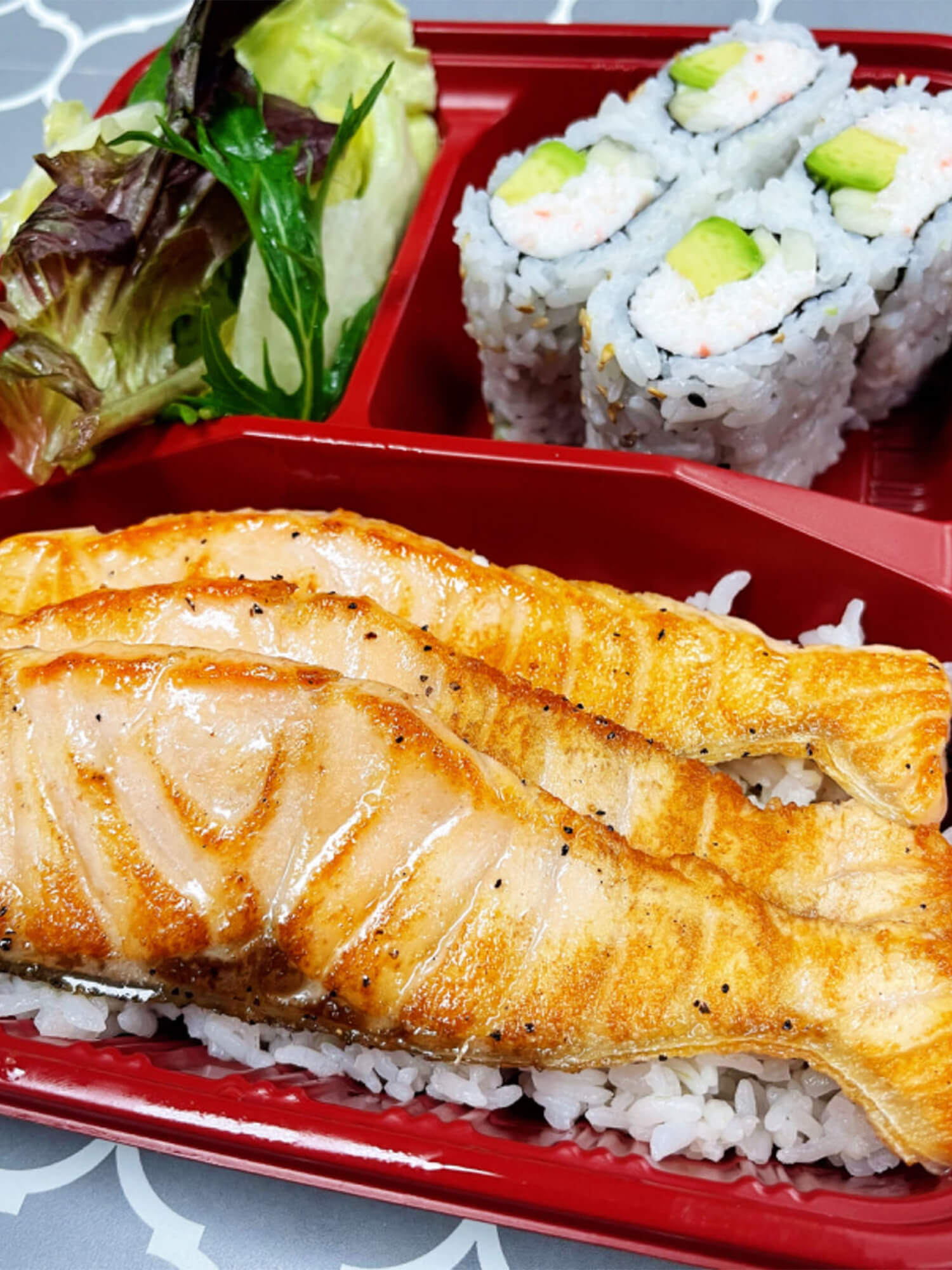 Aloha-Hawaiian-BBQ-&-Sushi-Asian-Fusion-restaurant-Grilled-Salmon-Bento-Box-Baldwin-Park Grilled salmon served with sushi rolls and a side of salad Sushi burrito with chicken, avocado, and vegetables at Aloha Hawaiian BBQ & Sushi, a Asian Fusion restaurant in Baldwin Park